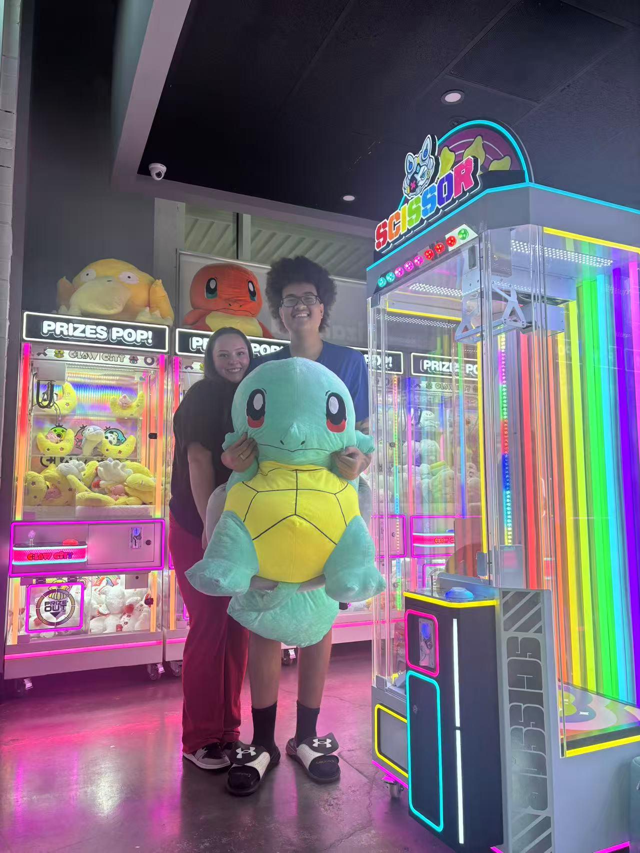 Two customers holding a giant Squirtle plush near claw machines at Dough valley, a Ramen Restaurant in Oregon City